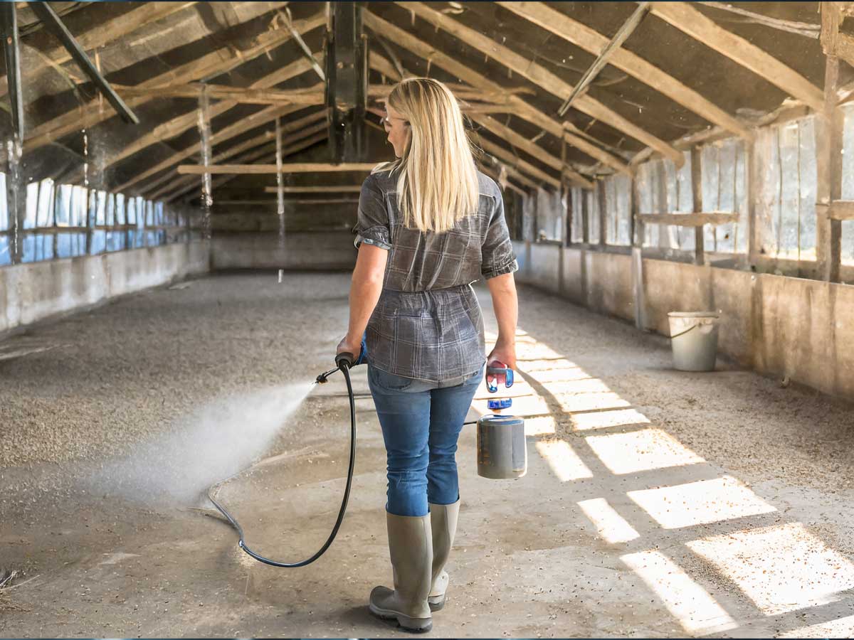 Farmer spraying barn floor