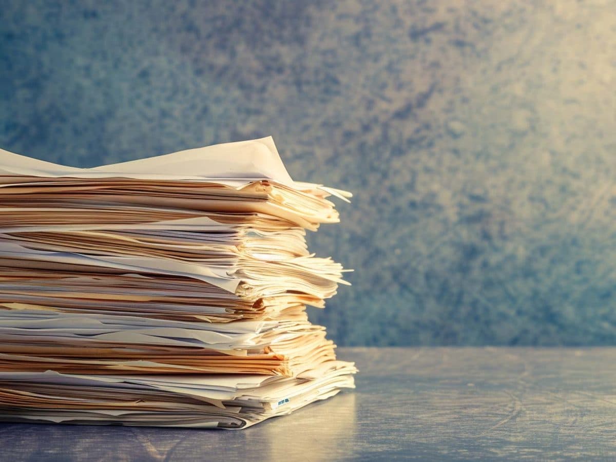 Policy documents on a desk beside a laptop