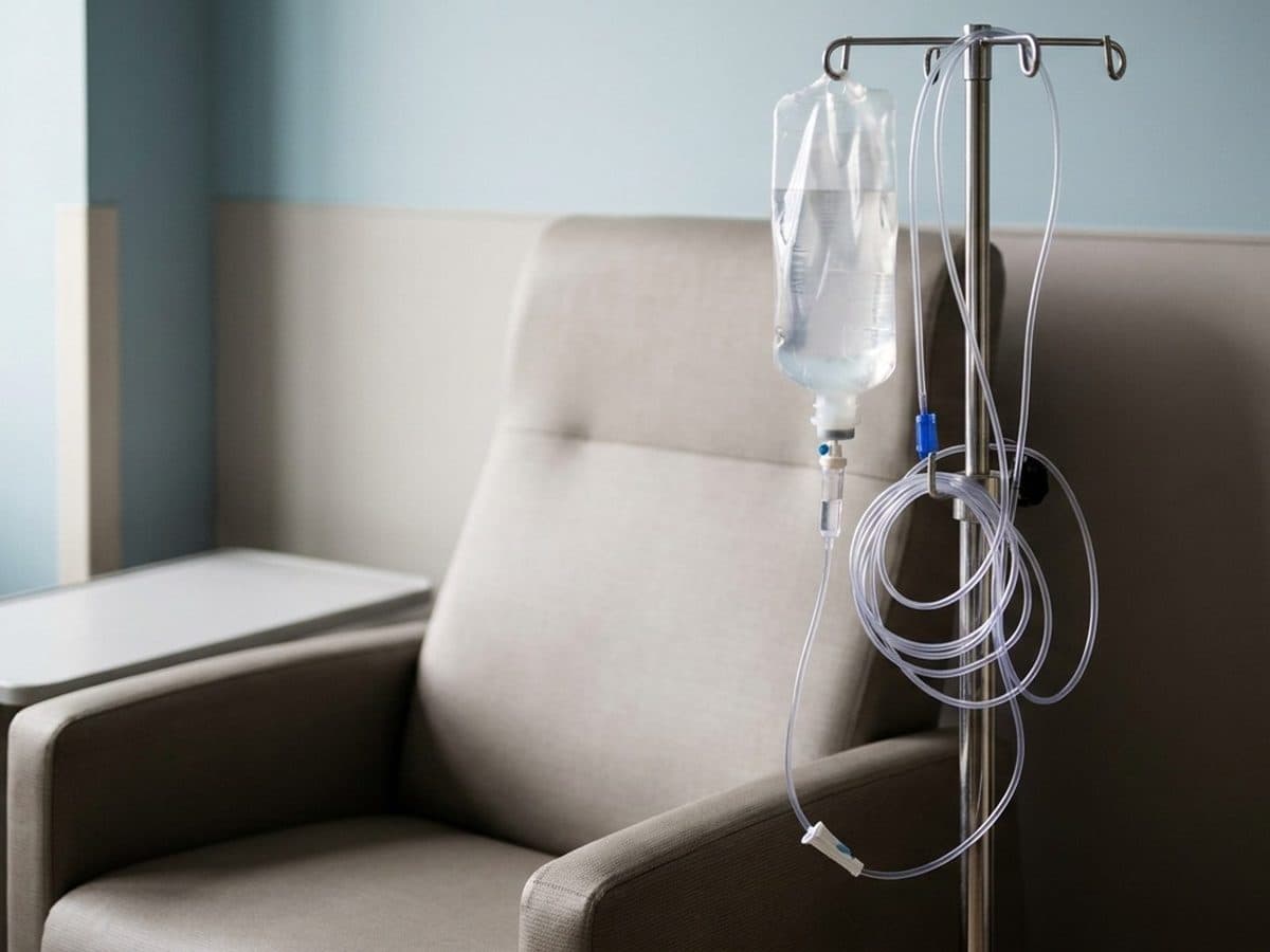 An unlabelled intravenous fluid bag beside an empty treatment chair