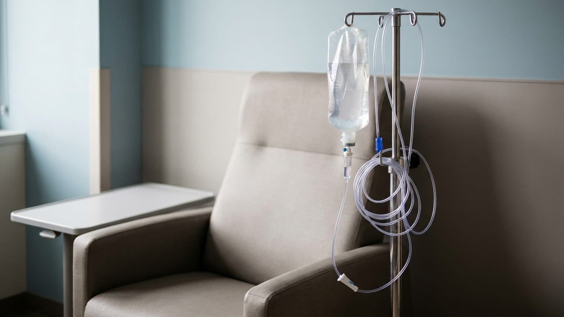 An unlabelled intravenous fluid bag beside an empty treatment chair